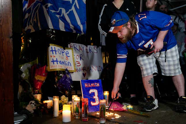 A well-wisher lights a candle at a makeshift tribute to the critically injured Bills defensive back.