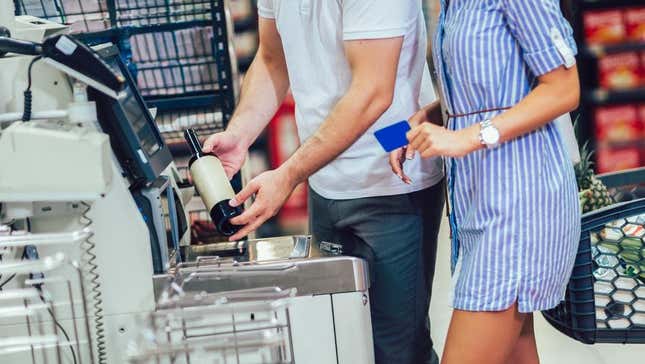 Couple scanning wine bottle at grocery store self-checkout