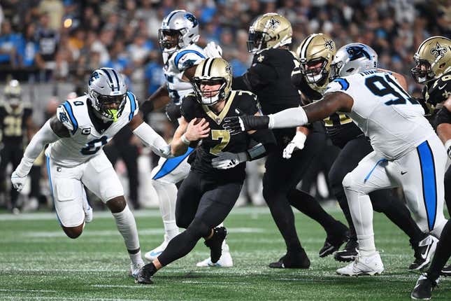 Sep 18, 2023; Charlotte, North Carolina, USA; New Orleans Saints quarterback Taysom Hill (7) with the ball as Carolina Panthers linebacker Brian Burns (0) and defensive end Nick Thurman (91) defend in the first quarter at Bank of America Stadium.