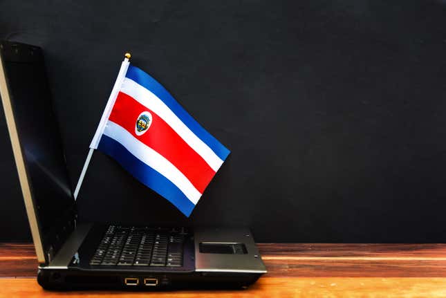 A Costa Rican flag standing behind a laptop.