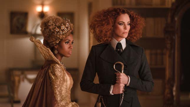 Kerry Washington in wig and ball gown stands next to red-haired Charlize Theron in a severe suit.
