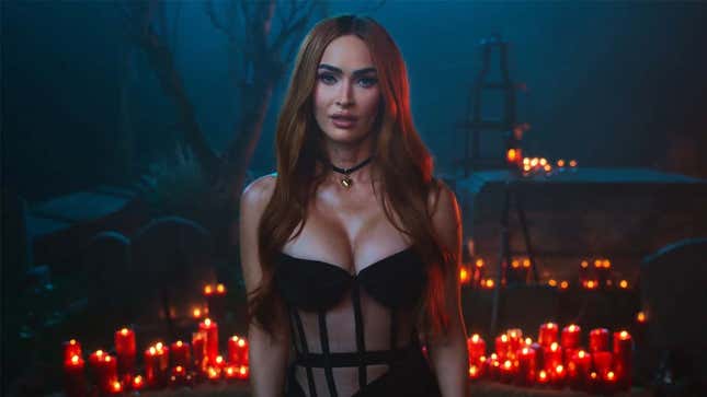 Acclaimed actress Megan Fox is standing in a black corset dress in front of a bevy of burning candles.