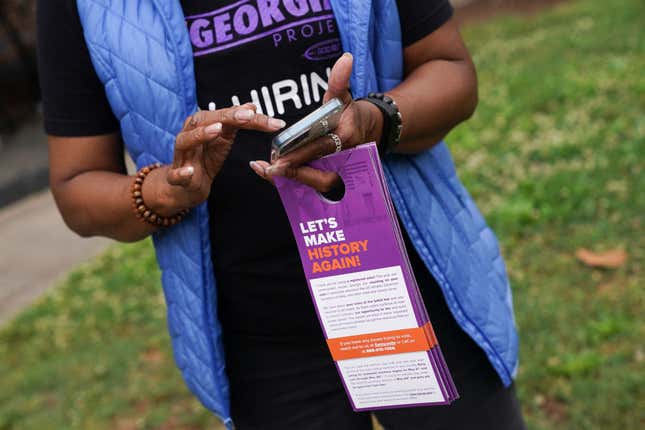 New Georgia Project canvasser Mardie Hill holds informational door hangers about the upcoming primary election on May 23, 2022, in East Point, Georgia.