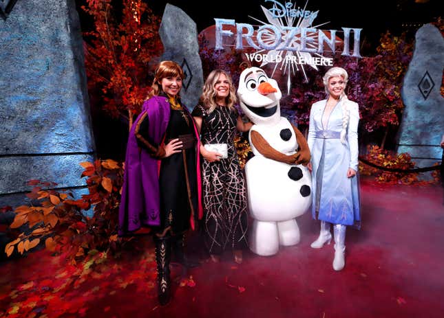 Director Jennifer Lee poses at the premiere for the film "Frozen II" next to three actors dressed as Anna, Elsa, and Olaf.
