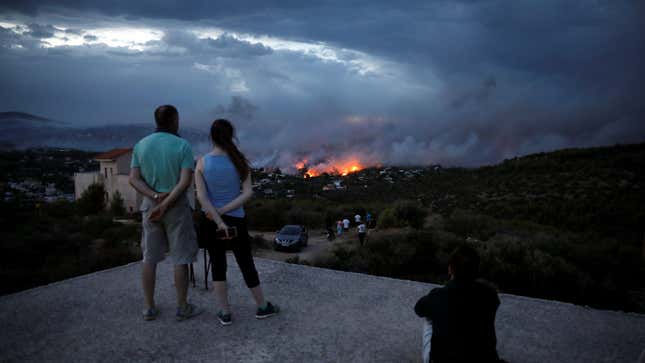 People watch a wildfire raging in the town of Rafina, near Athens, Greece.