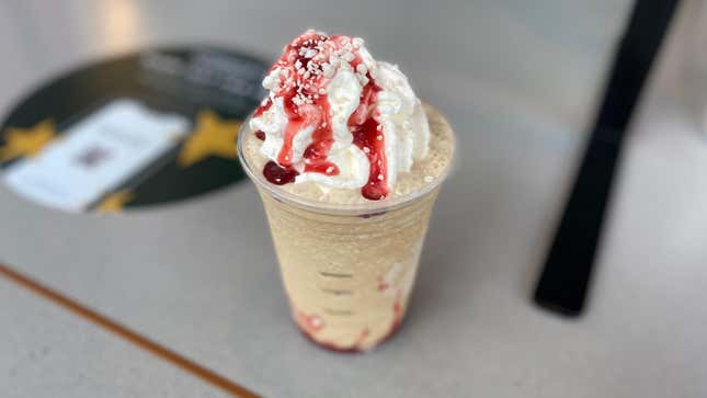 Starbucks' new Frappuccino sitting on Starbucks tabletop with whipped cream and red syrup drizzle