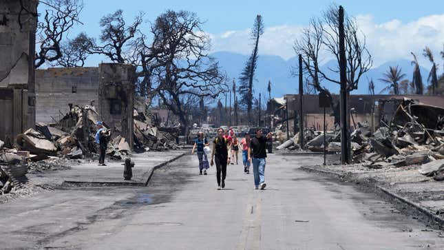 People walk along Main Street past wildfire damage on Friday, August. 11, 2023, in Lahaina, Hawaii.