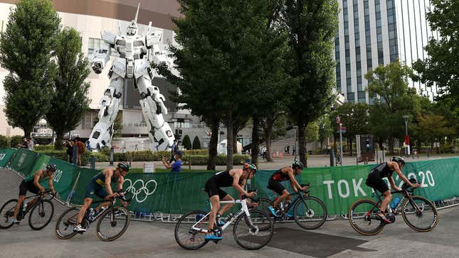 Olympic triathletes ride past the giant Gundam statue in Tokyo