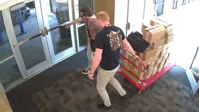 Two people walk out of the Indiana Convention Center with a giant pallet of boxes.