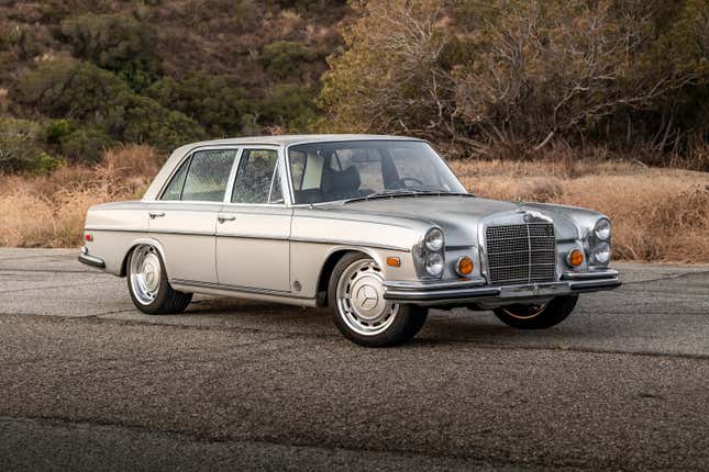 A silver 1971 Mercedes-Benz 300SEL 6.3 parked in front of some bushes, front-three quarter view.