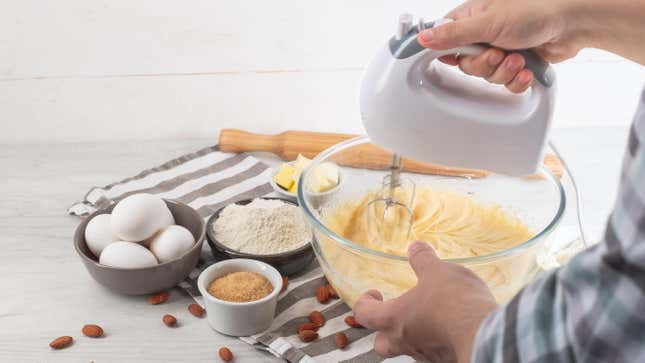A person mixing batter with a hand mixer.