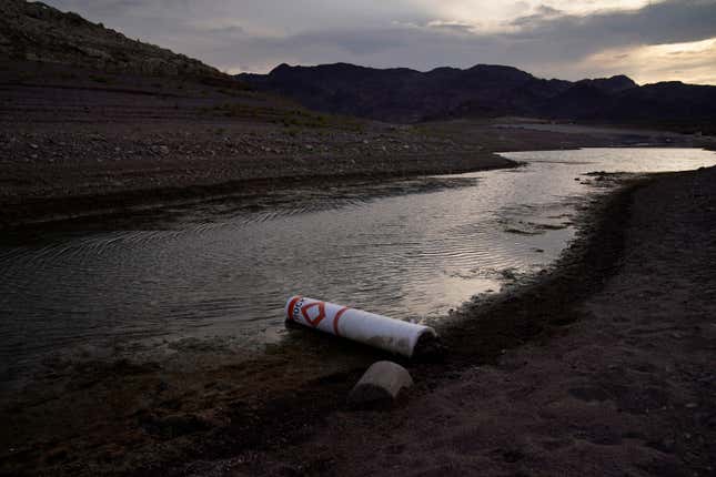 A buoy once used to warn of a submerged rock rests on the ground along the waterline near a closed boat ramp on Lake Mead. 