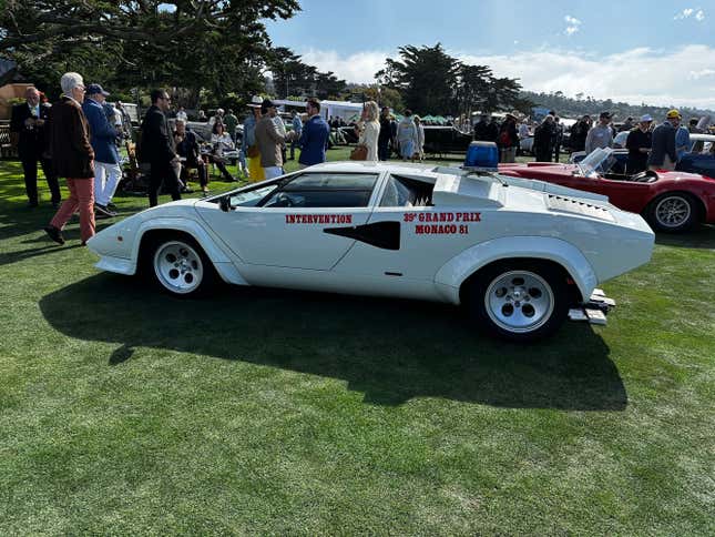 A white Lamborghini Countach safety car is parked on the green at Pebble Beach