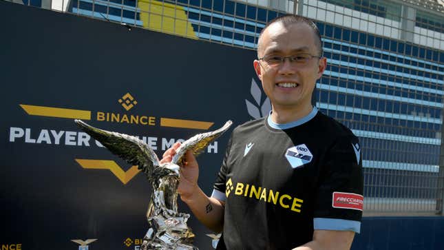 Binance CEO Changpeng Zhao holds a eagle statue in front of the Binance logo with the message "player of the moth"