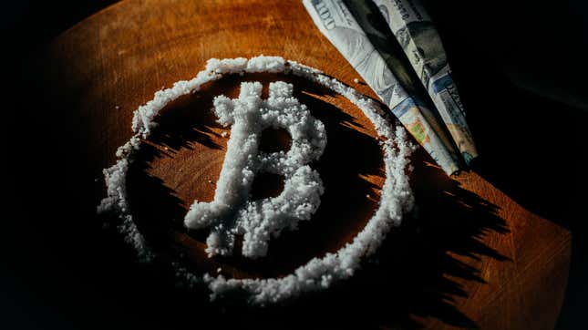 A bitcoin symbol drawn in white powder, as if to resemble cocaine, with a hundred dollar bill folded up like a paper airplane