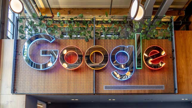An mirror sign with the Google logo is shown at the front desk. The sign is outlined in Google's blue, red, yellow, and green standard colors.