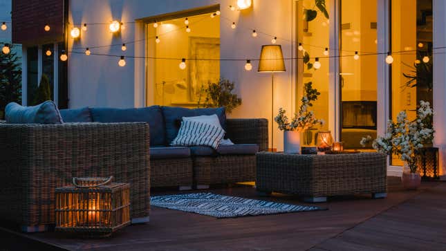 An outdoor deck in the evening with comfortable patio furniture and string lights hanging overhead