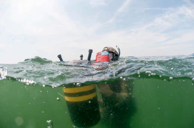 An ordnance disposal technician prepares an inert mine for countermeasure training.