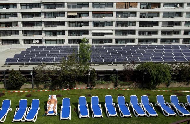 A man sunbathes at a rooftop spa next to solar cell panels on April 30, 2010 in Berlin, Germany.