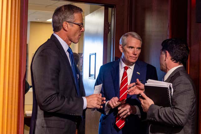 Sen. John Thune (R-SD) (L) and Sen. Rob Portman (R-OH) (C) talk with an aide before a press conference at the US Capitol on April 27, 2022 in Washington, DC