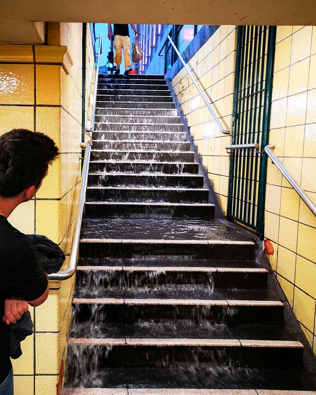 After heavy rainfall, water runs down the steps to the subway at Berlin Friedrichstra’e station.