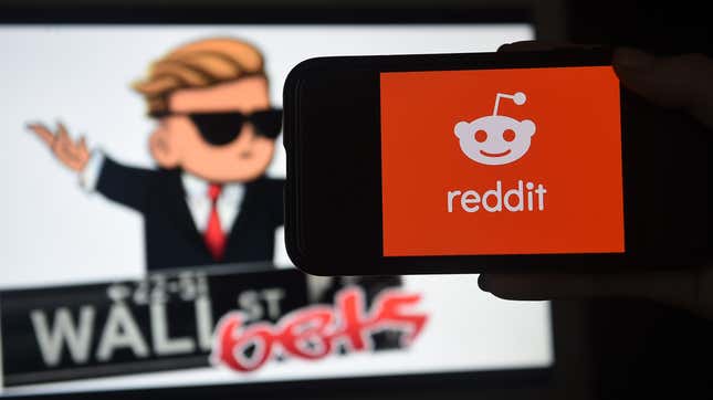 A phone showing the Reddit logo in front of a screen displaying the WallStreetBets logo.