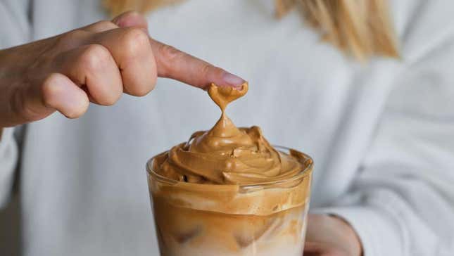 Finger touching dalgona coffee foam