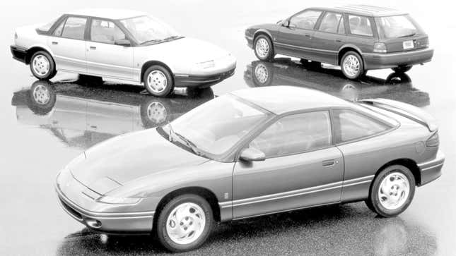 A black and white photo of three Saturn cars. 