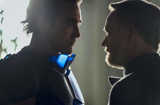 Lee Pace's Empire/Brother Day, wearing his blue armor stands very close to Jared Harris' Hari Seldon in Foundation. Both are shadowed.