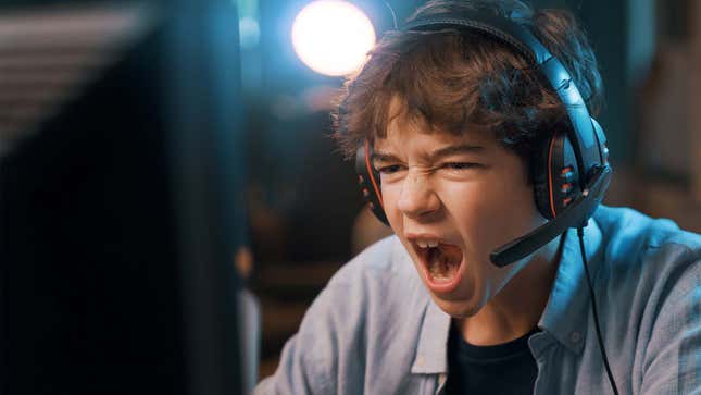 A young boy screams at a PC while wearing a headset. 
