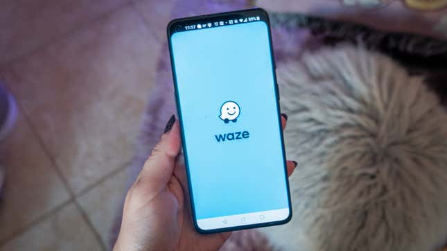 A photo of a person holding a phone with the Waze logo 