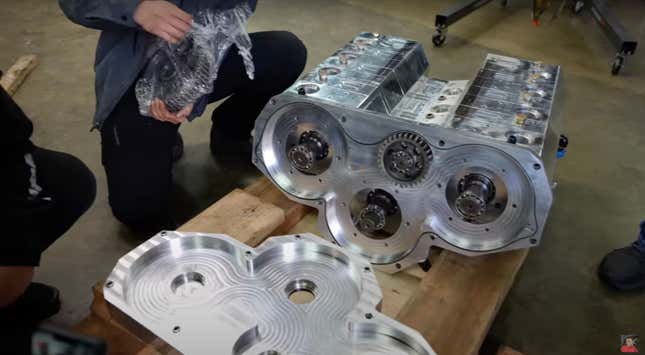 A milled aluminum 12-rotor engine is being disassembled on a wooden stand.