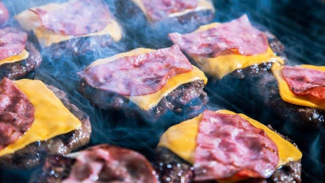Burgers with cheese and ham on grill