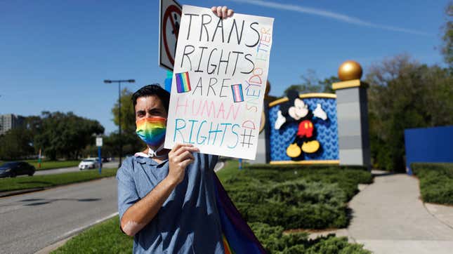 Disney employee Nicholas Maldonado holds a sign that reads "Trans Rights Are Human Rights" while protesting outside of Walt Disney World