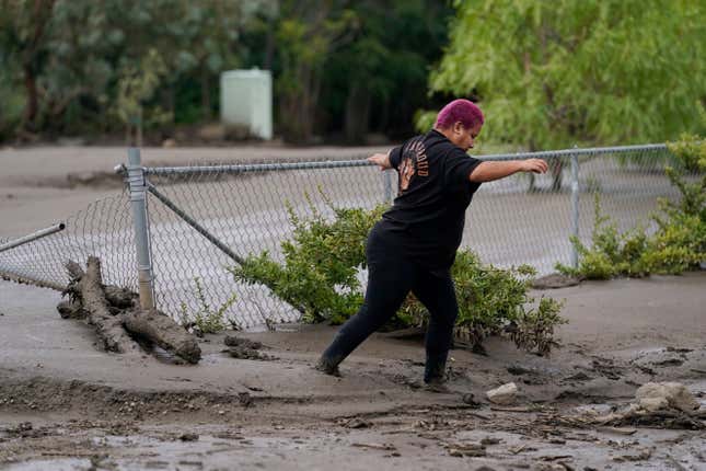 Local resident Perla Halbert walks through the mud along her driveway in the aftermath of a mudslide on Tuesday, Sept. 13, 2022, in Oak Glen, California. 