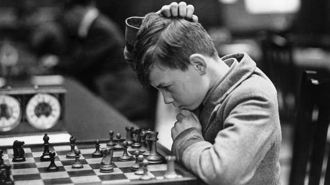A chess player looks down at his board while scratching his head.