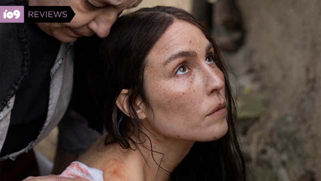 A woman looks blankly toward the sky as another woman cleans blood off her shoulder in a scene from You Won't Be Alone.