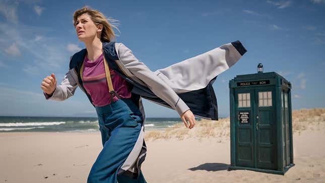 Jodie Whittaker's 13th Doctor walks through a windswept beach, away from the TARDIS.