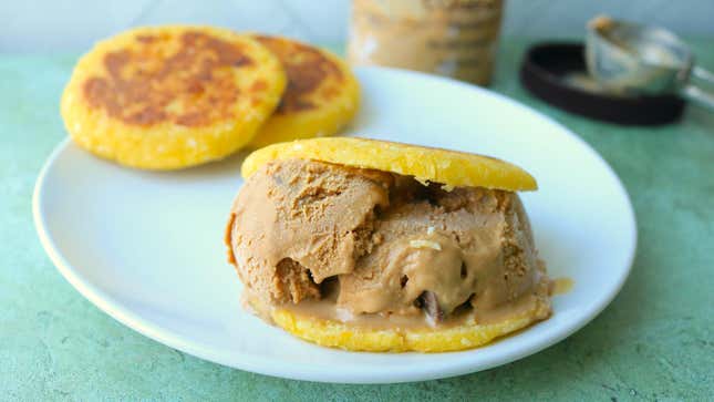 Yellow, sweet corn arepa filled with caramel ice cream sits on a plate.