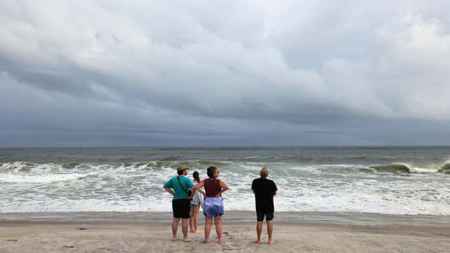 People look at incoming waves on the beach at Robert Moses State Park on the eve of landfall by Hurricane Henri.