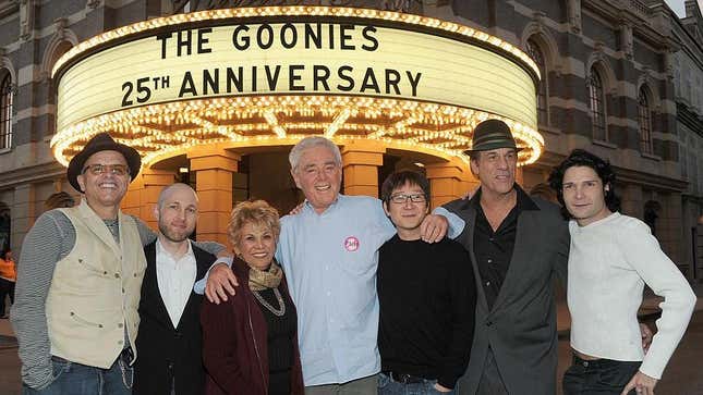 Richard Donner (center) stands in front of a theater marquee at The Goonies’ 25th anniversary celebration with (from left): Joe Pantoliano, Jeff Cohen, Lupe Ontiveros, Ke Huy Quan, Robert Davi, and Corey Feldman.