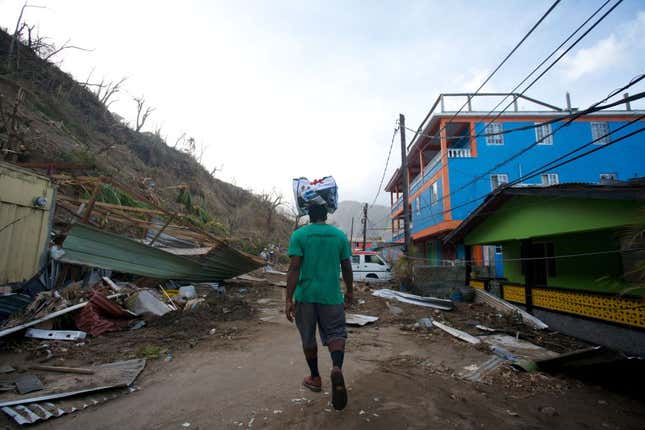 A man carries water on his head on September 23, 2017 in Newtown on the Caribbean island of Dominica following Hurricane Maria. 