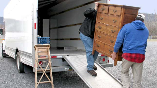 two men moving a dresser onto an empty moving truck