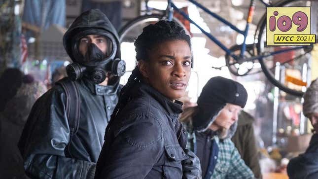 The live-action's Y: The Last Man's Yorrick wears his large raincoat, hood, and gas mask in a busy marketplace while Agent 355 look concerned.