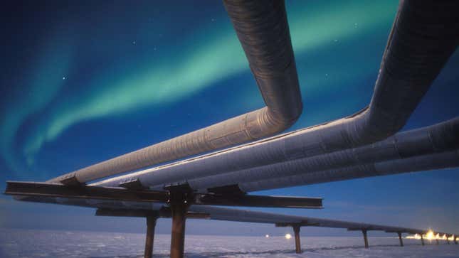 A full moon helps illuminate the Alaskan pipeline under the faint glow of the Aurora Borealis near Milne Point, Alaska.