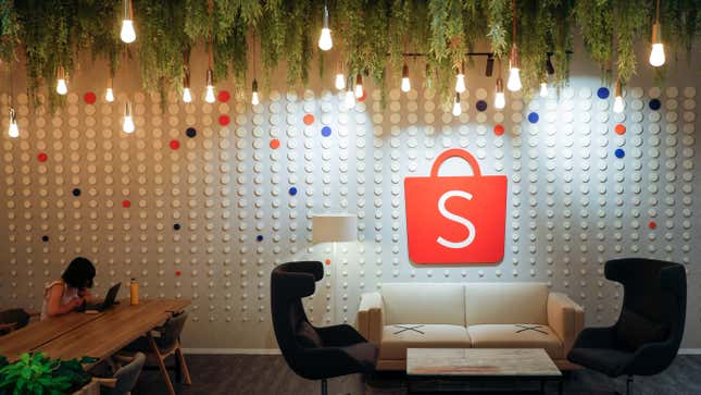 A person sits near a sign of Shopee at its office in Singapore