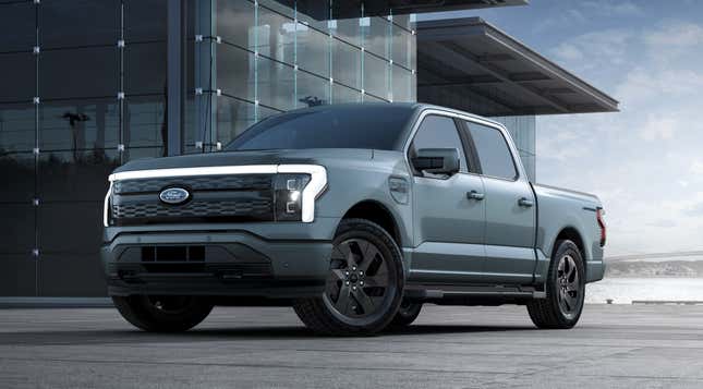 A light blue 2023 Ford F-150 Lightning is parked in front of a glass building.