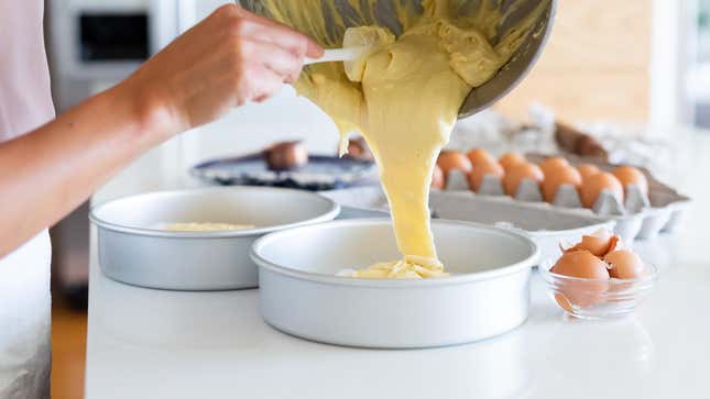 A person pouring batter into a cake pan.