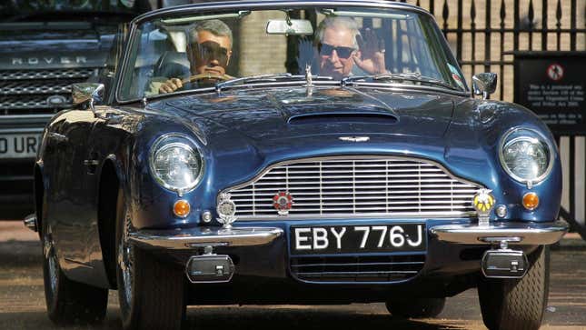 Prince Charles, right, waves as he leaves his official residence Clarence House in London in his vintage Aston Martin with an unidentified driver.