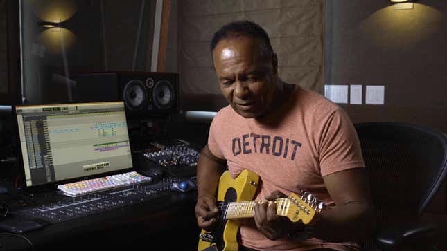 Ray Parker Jr. plays guitar in front of a computer.
